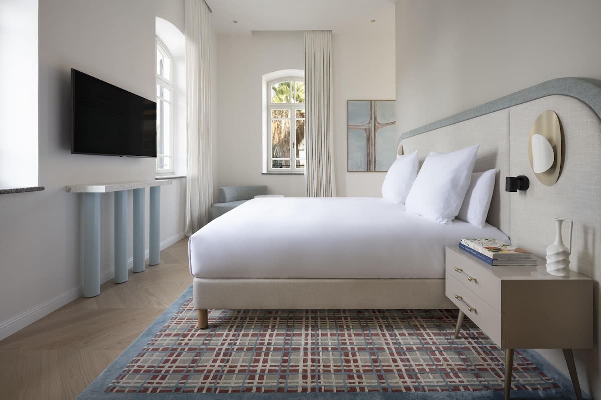 Una camera da letto moderna con un letto grande, una televisione, un comodino e una finestra con tende.