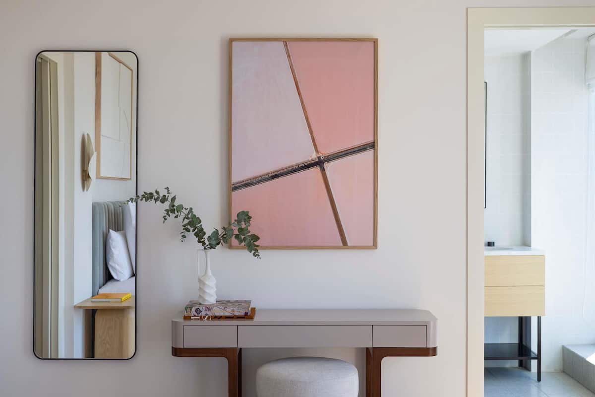 Una camera moderna con uno specchio, un comodino, una panca e un quadro.