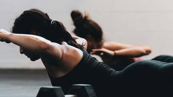 A person lying on the floor, possibly in a gym or workout area, with a dumbbell nearby.