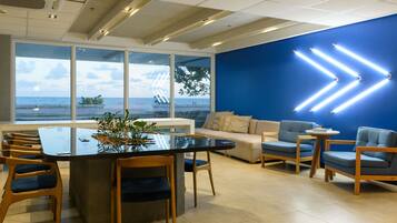 A modern office space with a large table, chairs, a sofa, and a blue accent wall.