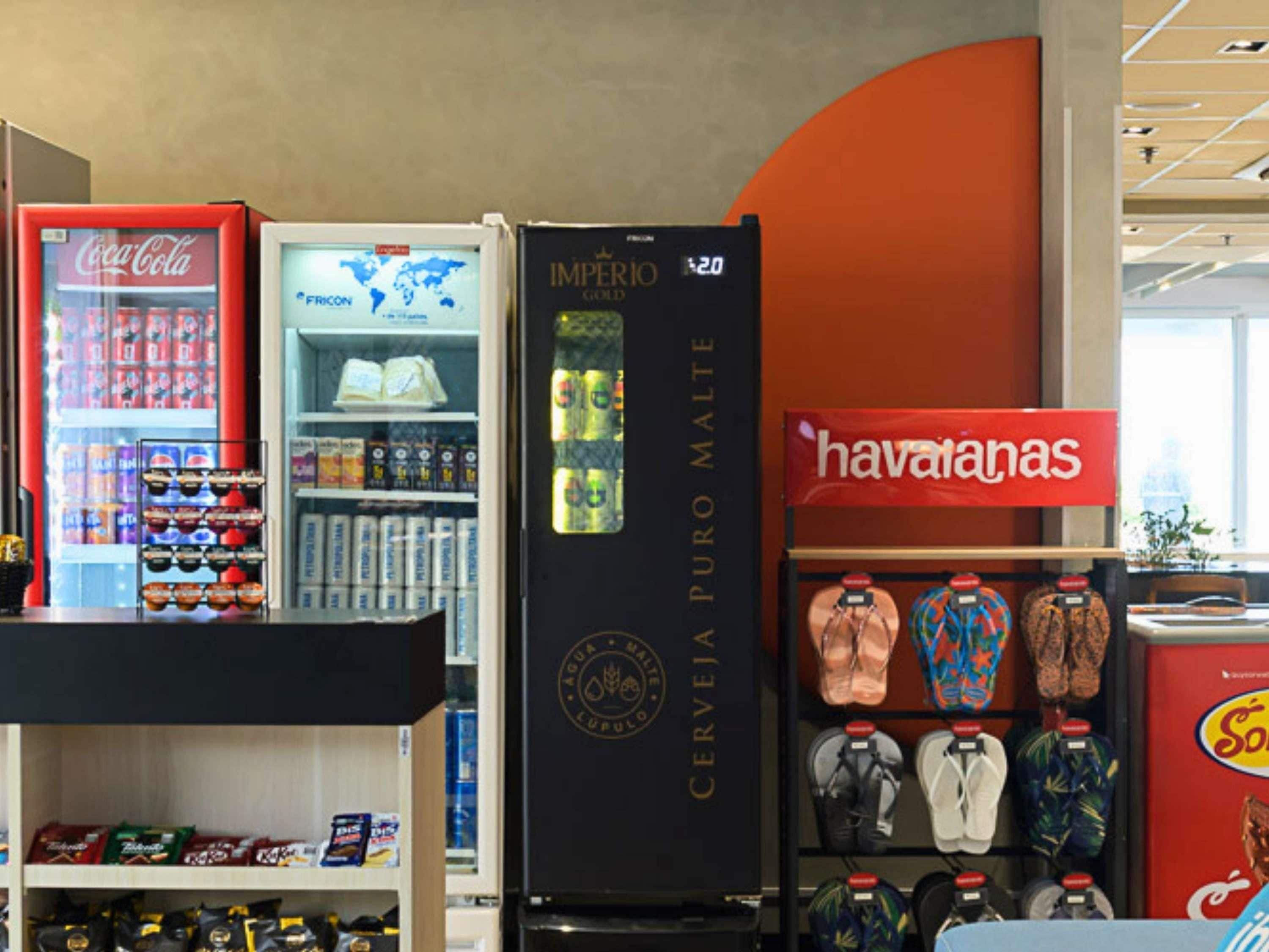 Un magasin avec un réfrigérateur Coca-Cola, un autre réfrigérateur portant l’inscription « IMPERIO GOLD », et un rayon consacré aux sandales de la marque « havanas ».