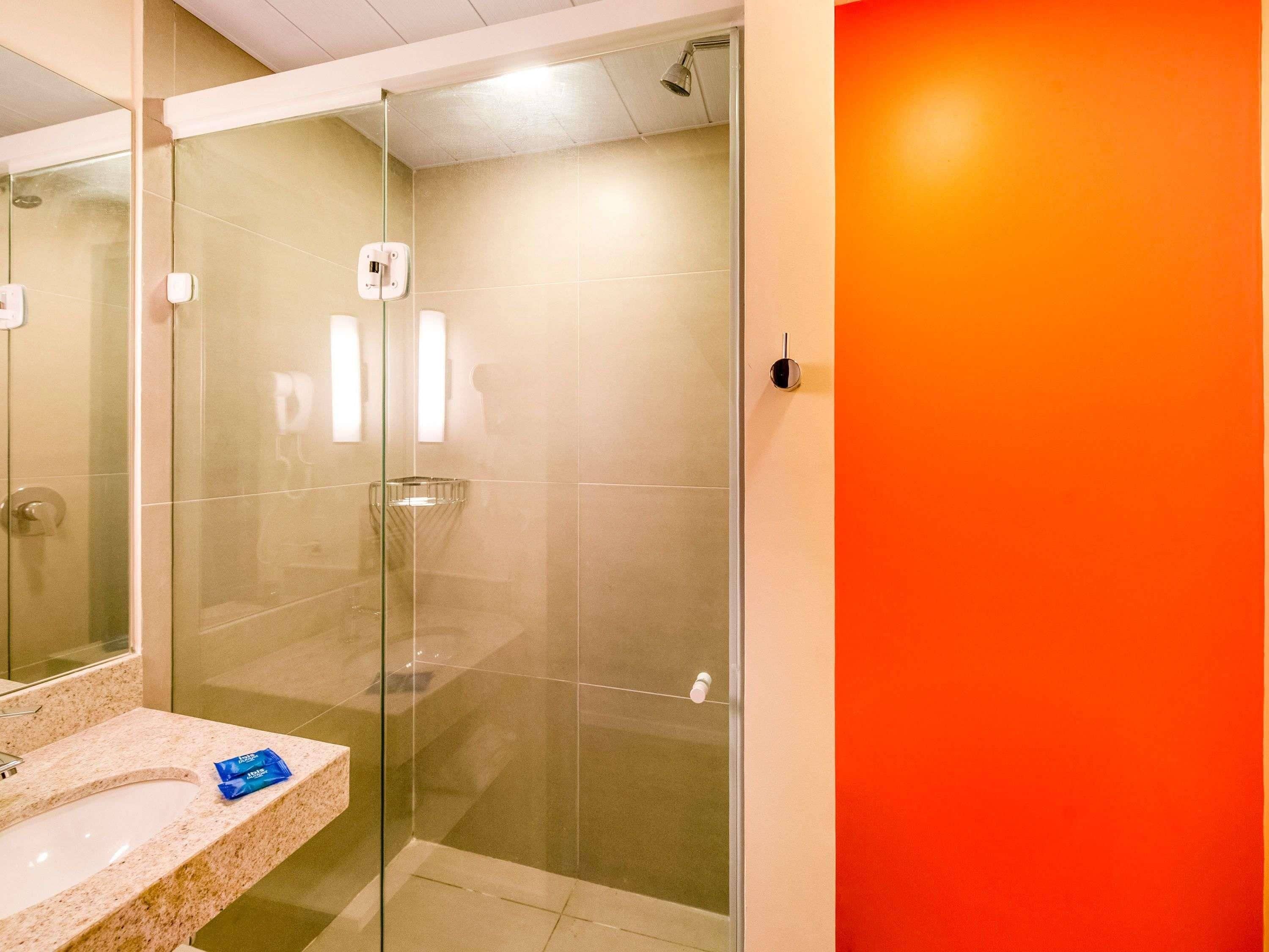 A bathroom with a glass-enclosed shower, a sink with a marble countertop, and a mirror.