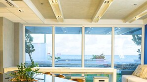 A modern interior with a dining area, large windows, and a view of the sea. - ibis budget Recife Jaboatão (Jaboatão dos Guararapes)