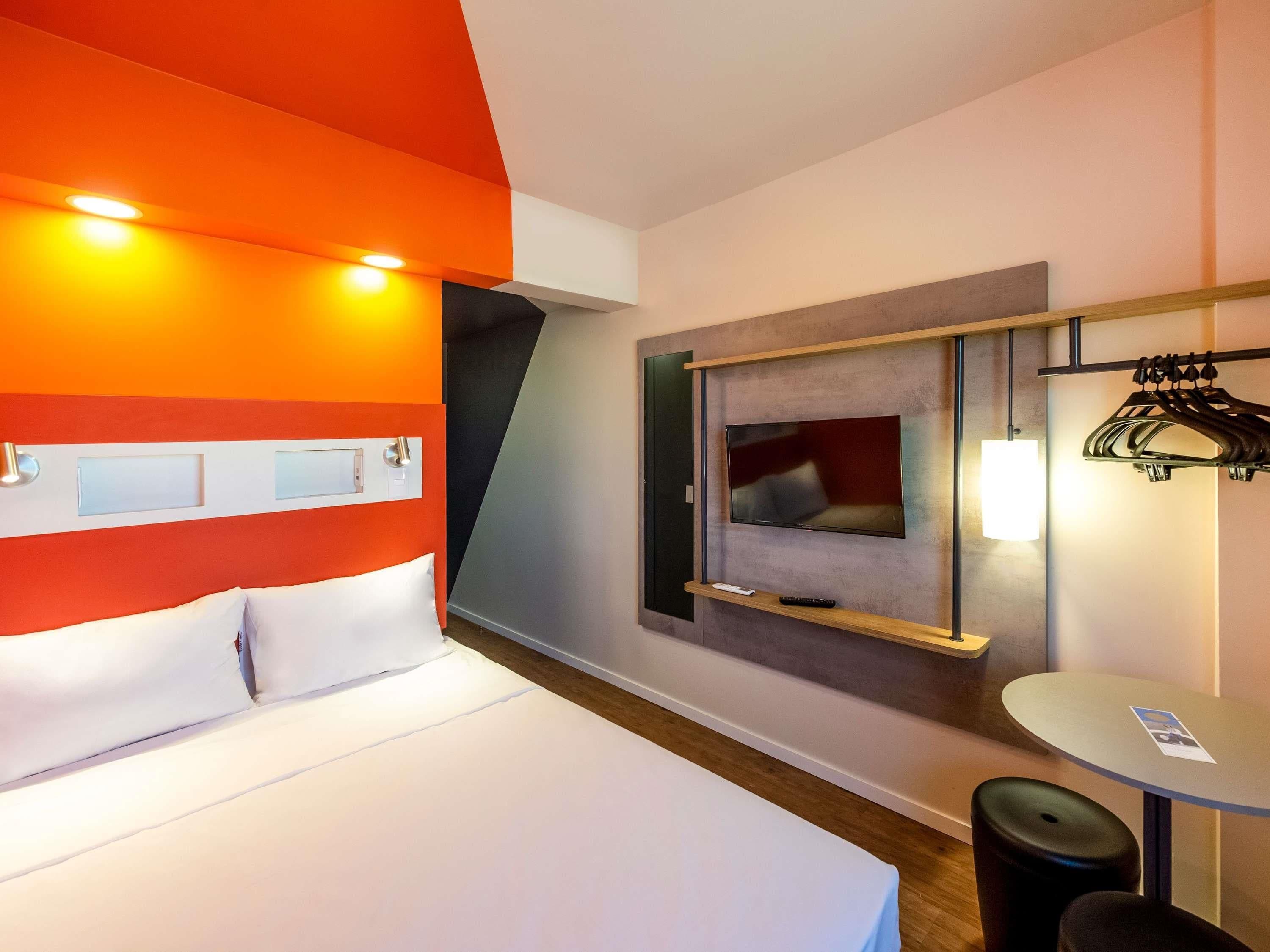 Une chambre d’hôtel comprenant un lit, une télévision, une petite table et un coin salon.