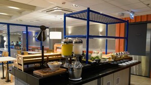 Een buffetgedeelte met een bedieningspunt, een koffieapparaat en diverse gerechten.