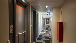 A hotel corridor with a checkered floor, a fire alarm, and a wheelchair accessibility sign. - ibis budget Recife Jaboatão (Jaboatão dos Guararapes)