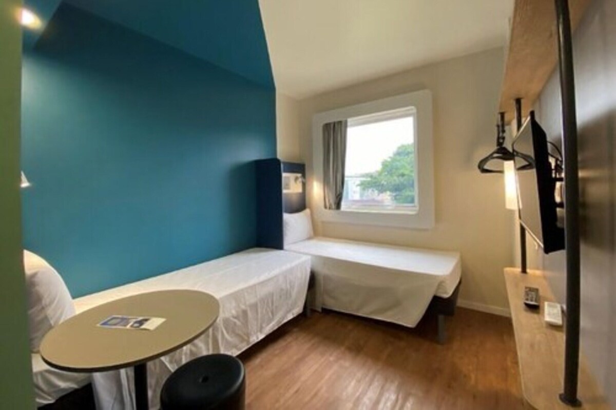 A compact room with a bed, a small table, and a window.