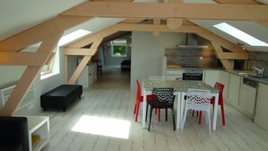 Eine Loft-Küche mit Essbereich, ausgestattet mit Dachfenstern, Holzbalken und Blick ins Freie.
