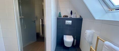 Un baño moderno con ducha, inodoro y tragaluz.