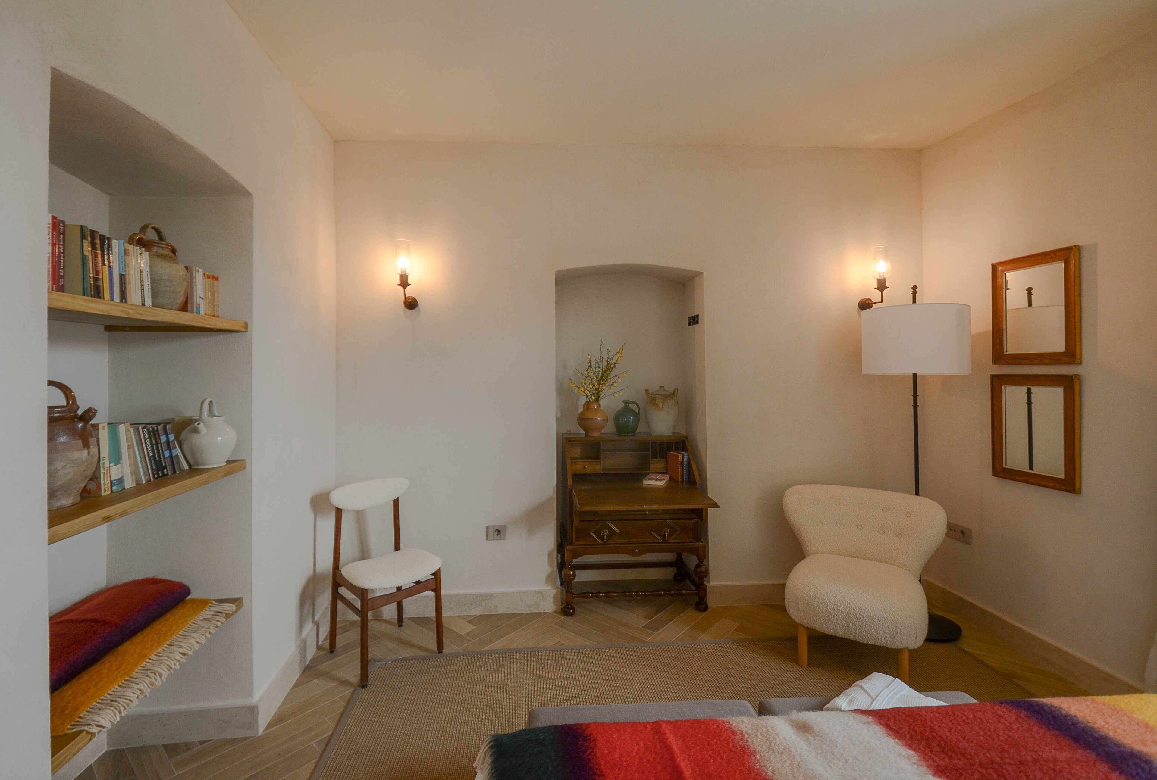 Ein Zimmer mit Holzstuhl, Schreibtisch, Bücherregal und Lampe.
