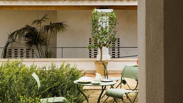 Un patio con techo de tejas, una mesa con sillas y una planta en maceta.