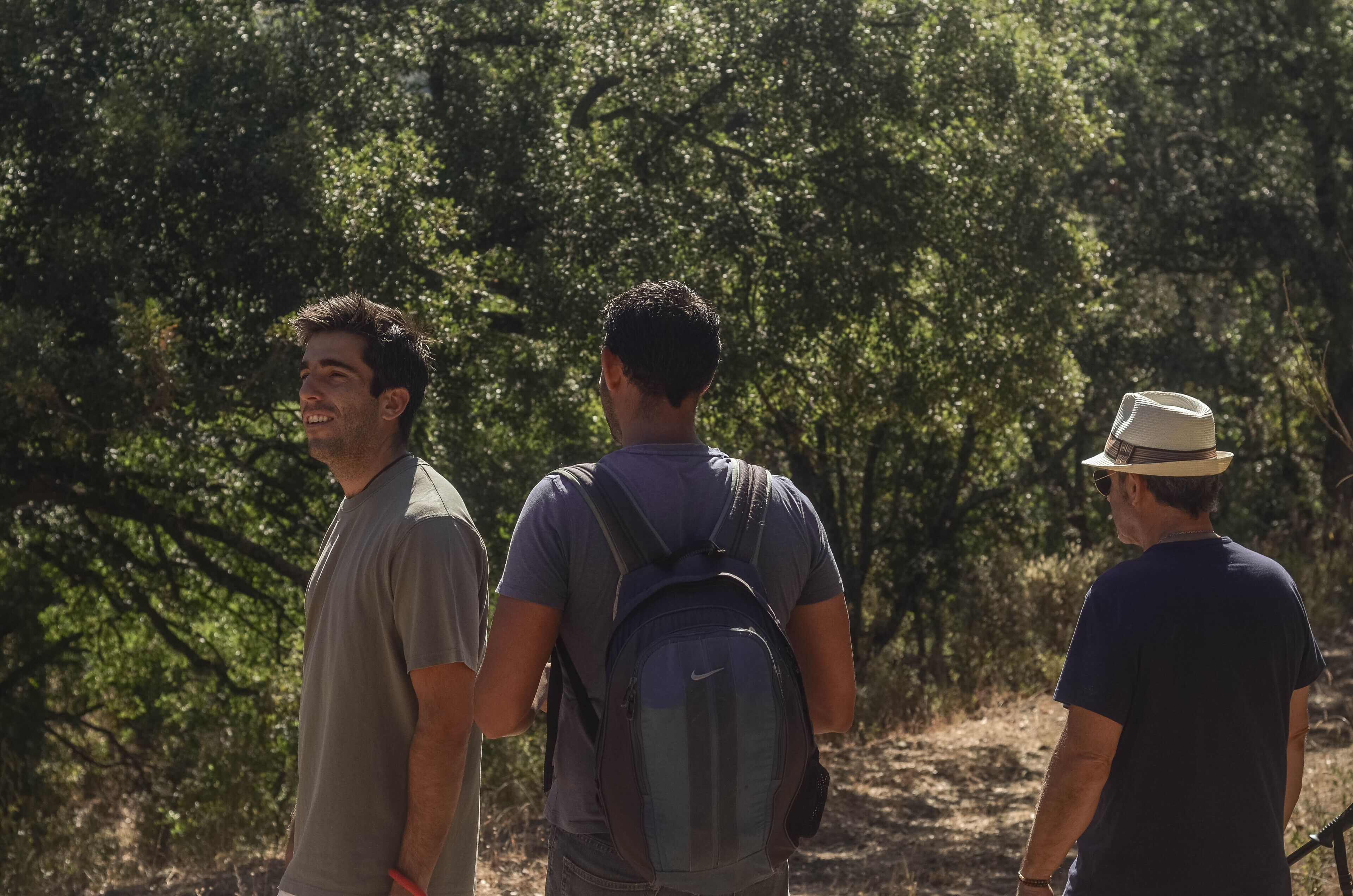 Tres personas caminando por un sendero rodeado de abundante vegetación.