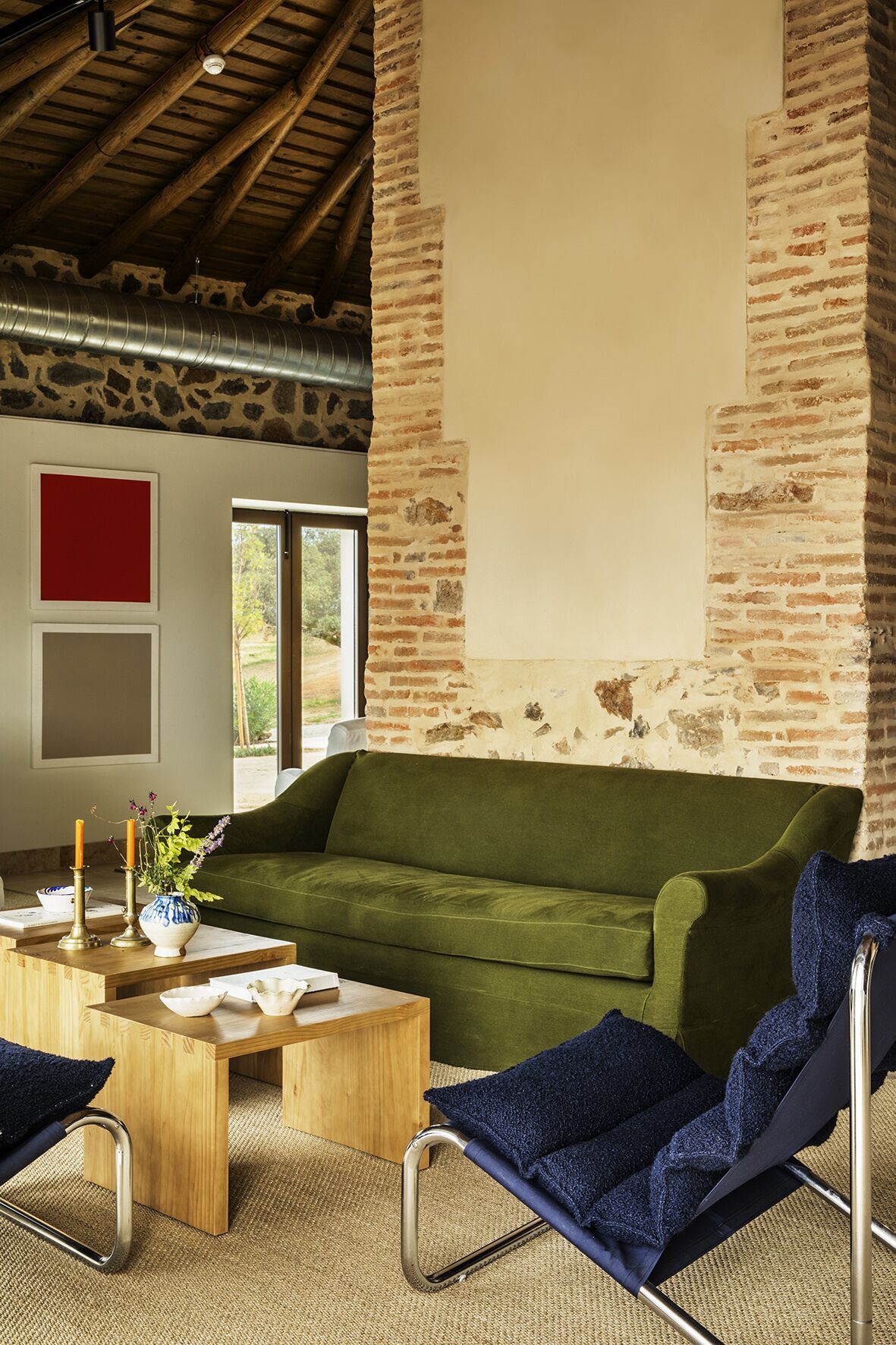 Una habitación acogedora con un sofá verde, una mesa de centro de madera y una silla azul.