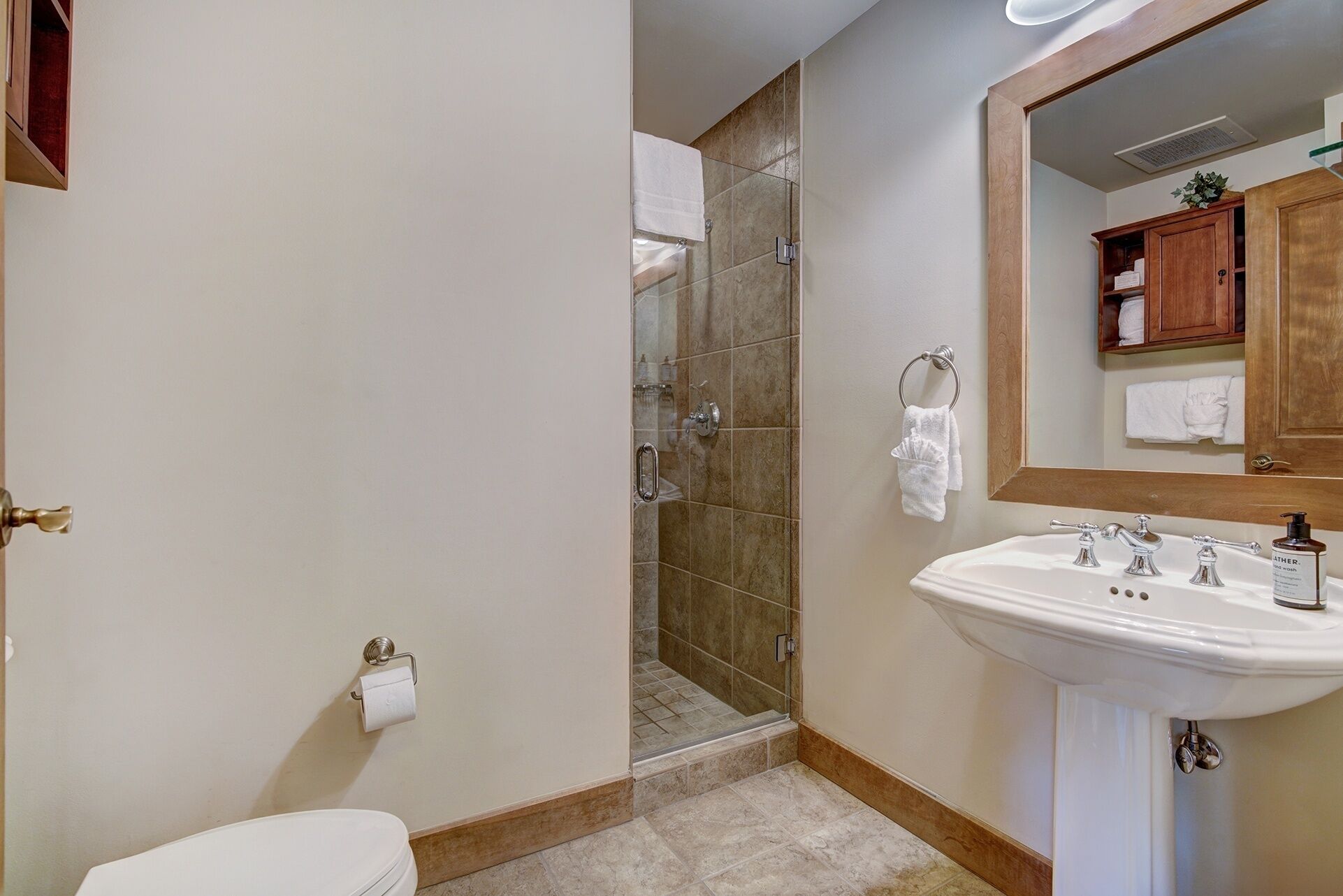Ein Badezimmer mit Dusche, Toilette, Waschbecken und einem Holzkabinent.