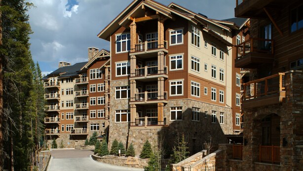 A multi-story hotel with balconies, stone facade, and a central courtyard.