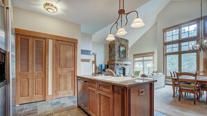 A spacious kitchen with a large island, wooden cabinets, and a stone fireplace.