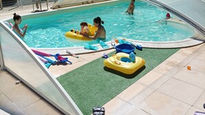 A swimming pool with inflatable toys and a covered area.