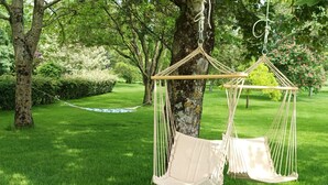 A hammock suspended from a tree in a lush green park.