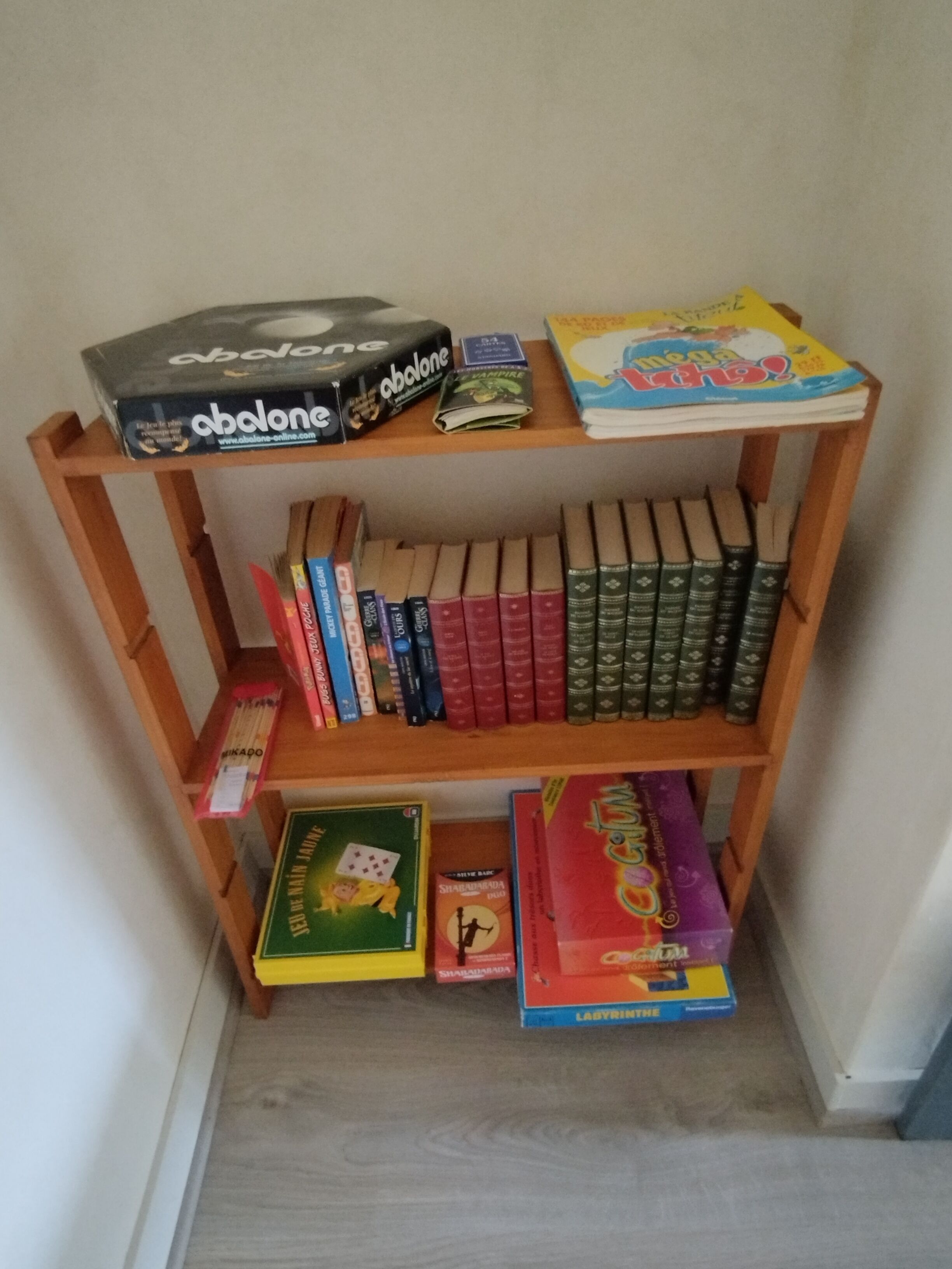 Ein Bücherregal aus Holz mit verschiedenen Brettspielen und Büchern.