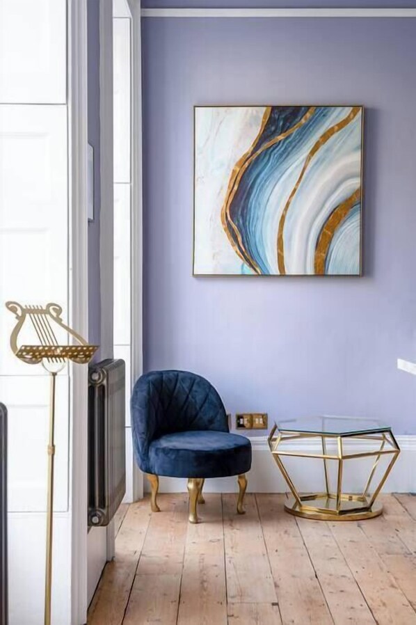 A room with a blue velvet chair, a geometric glass table, and a marble-patterned painting on the wall. - Darcy's View – super stylish stay in city centre (Bath)