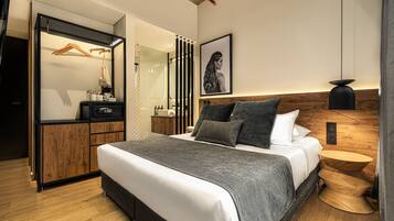 A modern bedroom with a large bed, a wooden wardrobe, a mirror, and a bedside table with a lamp.