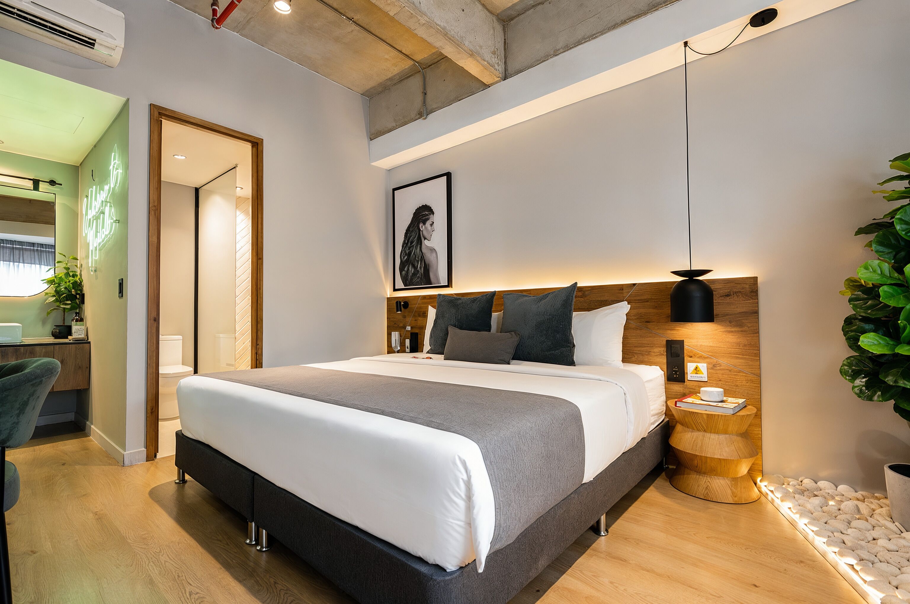 Un dormitorio moderno con una cama grande, una mesita de noche y un cuadro enmarcado en la pared.
