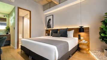 A modern bedroom with a large bed, bedside table, and a framed picture on the wall.