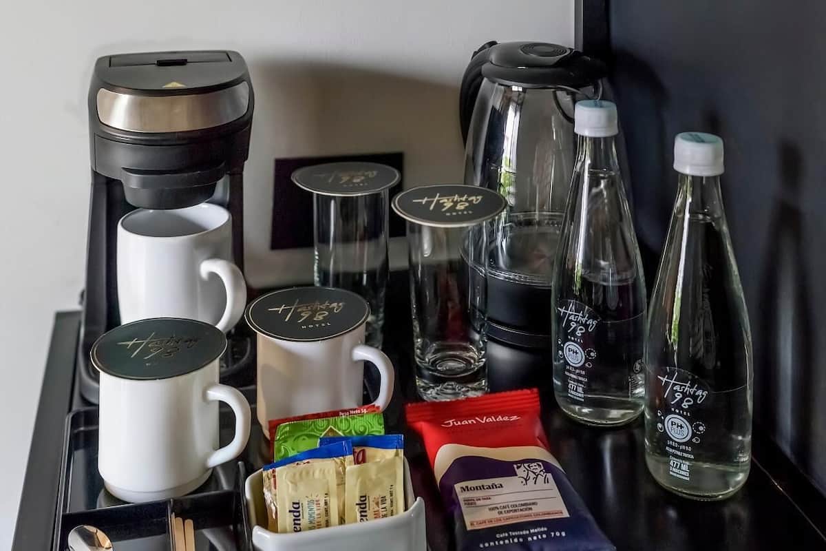 A tray with coffee maker, mugs, water bottles, and condiments.
