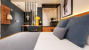 Une chambre d’hôtel moderne, équipée d’un lit, d’un bureau, d’une chaise, d’une lampe et d’un tableau encadré au mur.