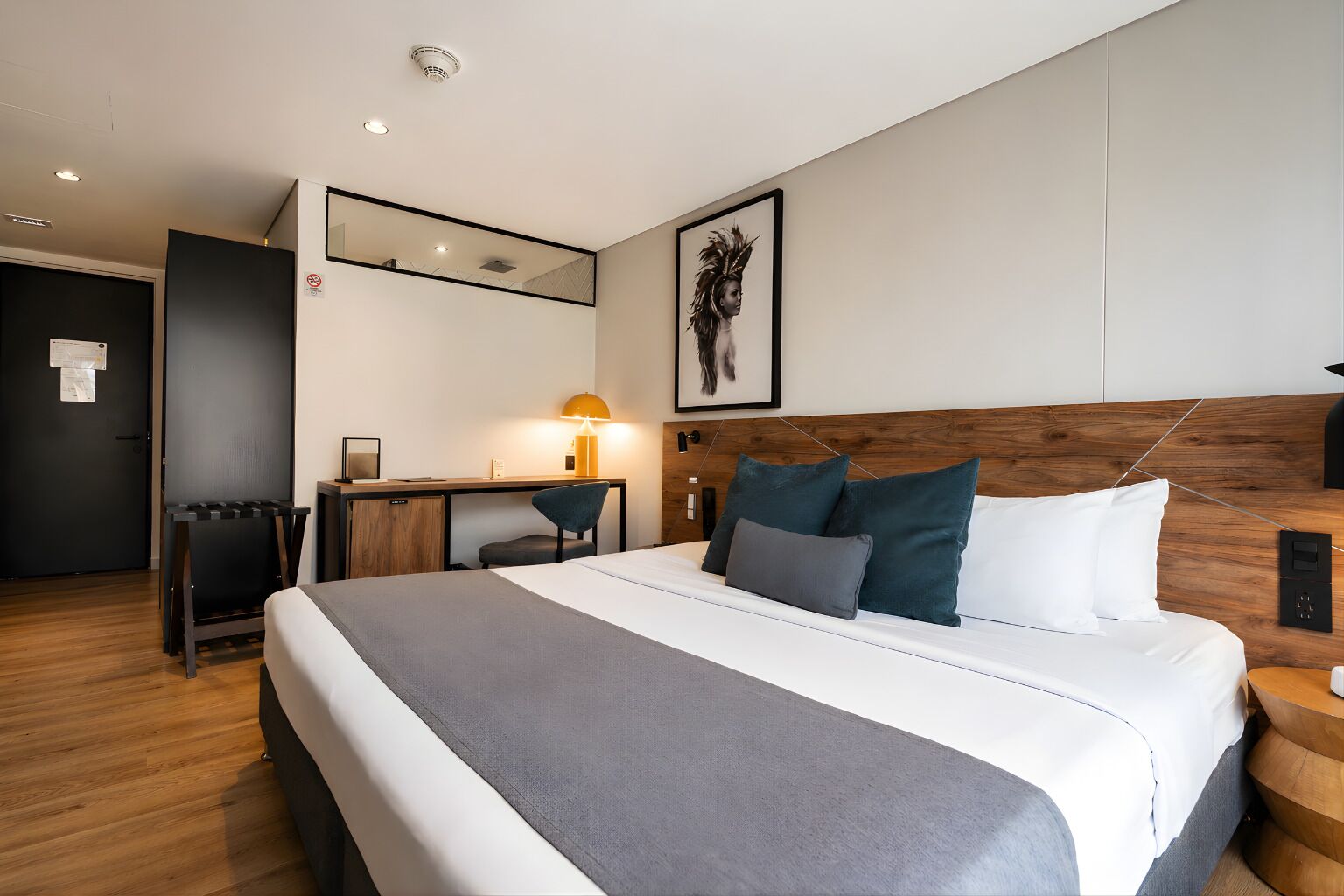 Una habitación de hotel moderna con una cama grande, un escritorio y un espejo.