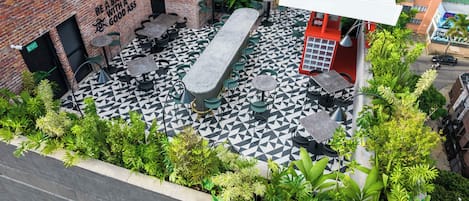 An outdoor seating area with a long bench, chairs, and a patterned floor.
