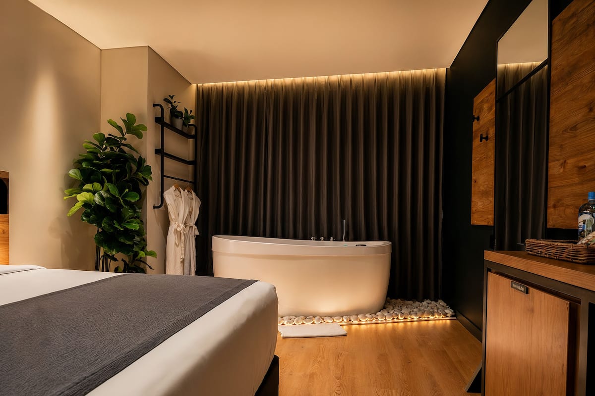 A modern bathroom with a bathtub, a wooden vanity, and a potted plant.