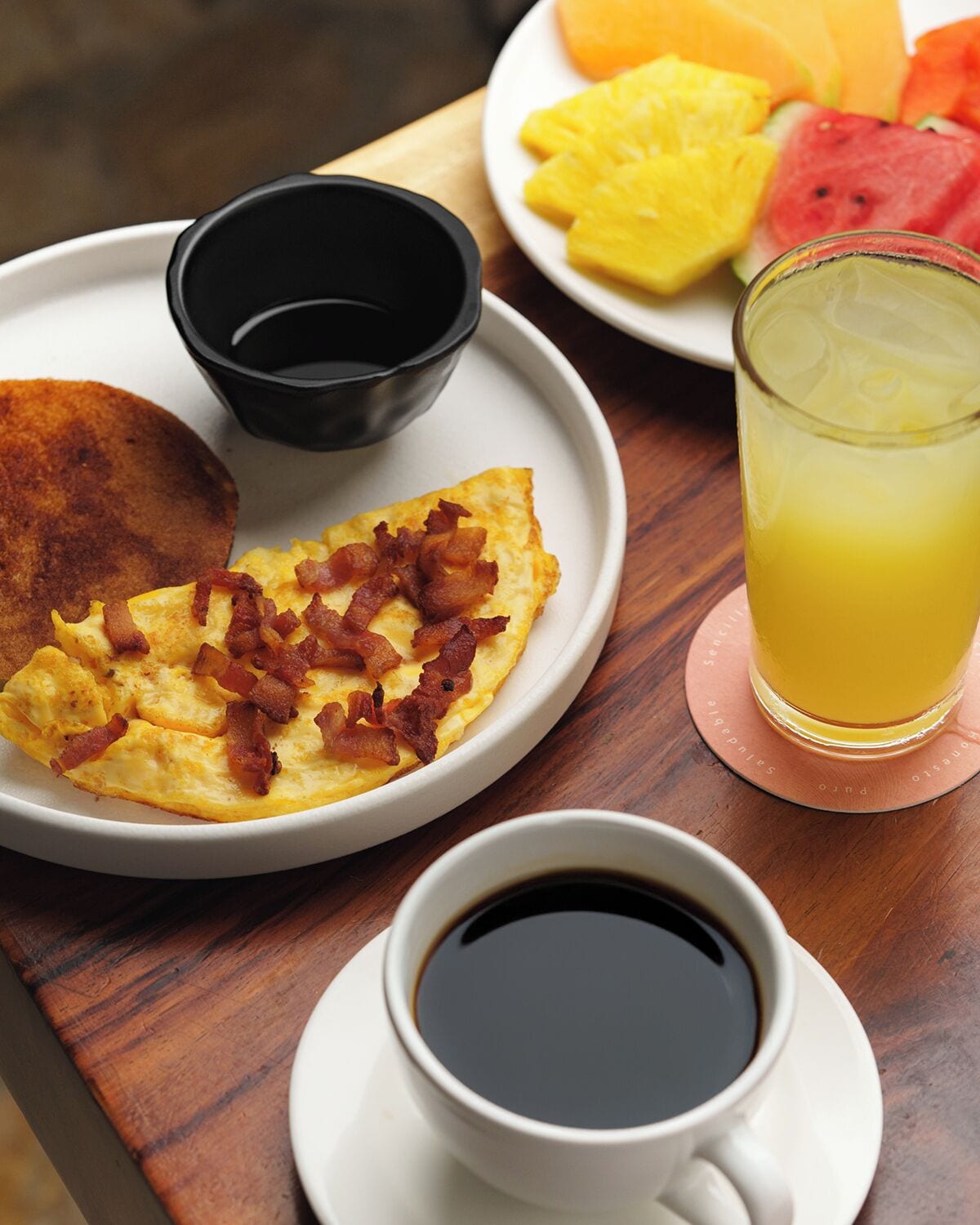 A breakfast tray with eggs, bacon, toast, juice, and coffee.