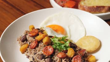 Un plato de arroz frito con frijoles, tomates y un huevo frito.