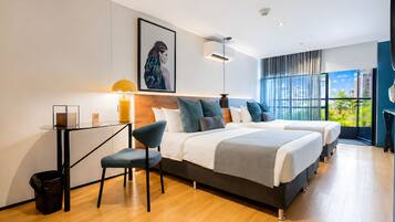 A modern hotel room with two beds, a desk, and a large window.