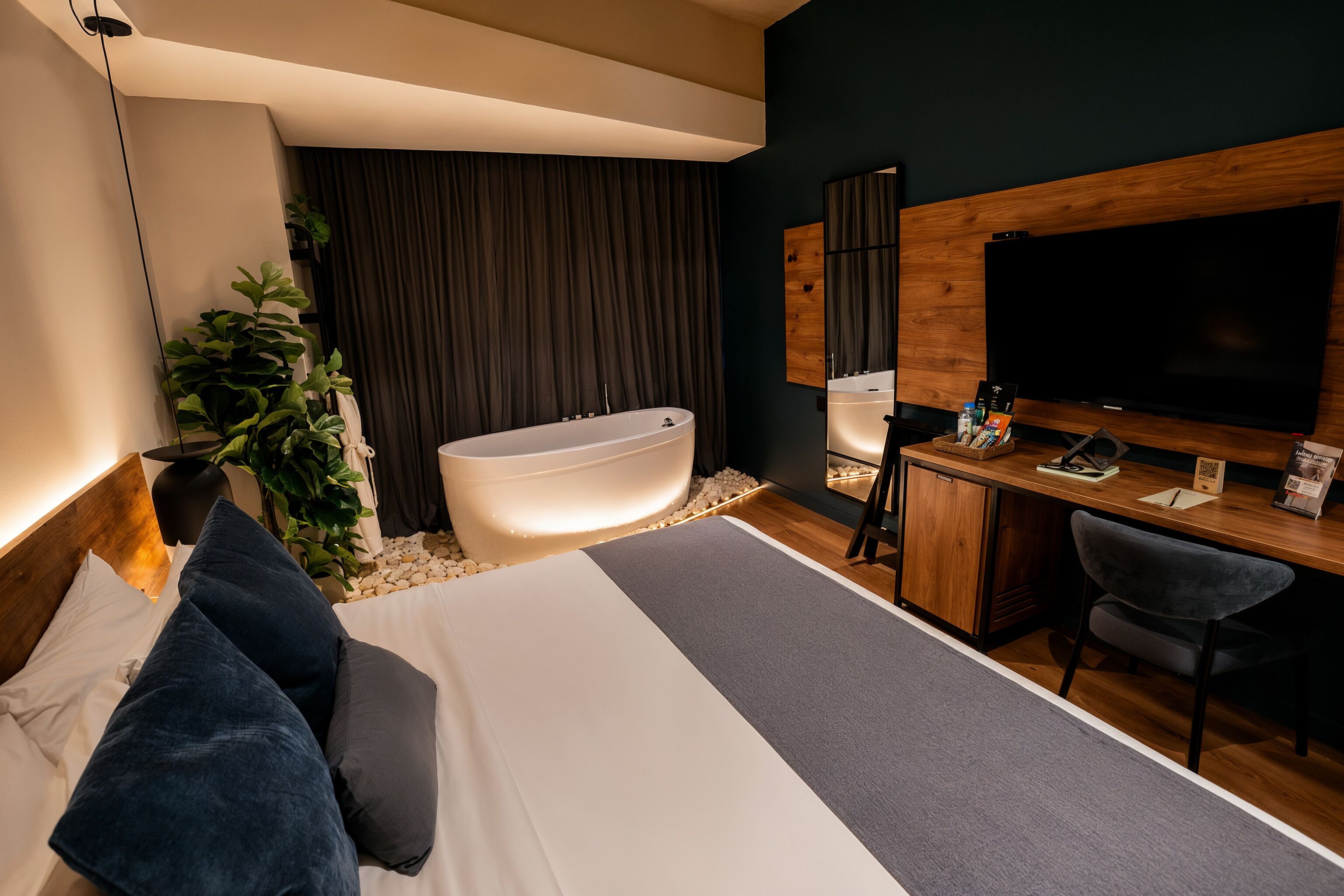 Una habitación de hotel moderna con una cama grande, una bañera, un escritorio con silla y un televisor.