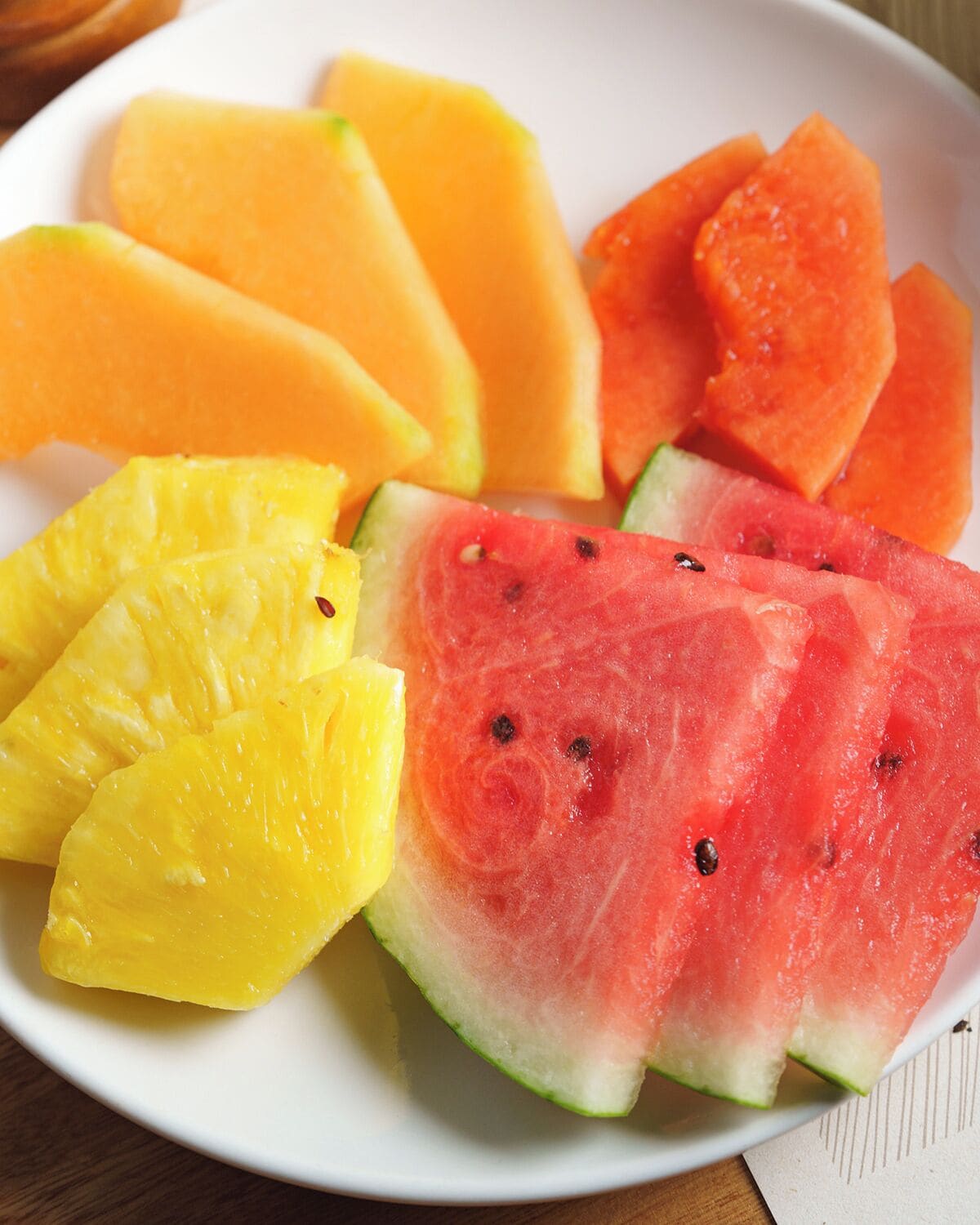 A plate of sliced fruits including pineapple, watermelon, and cantaloupe.
