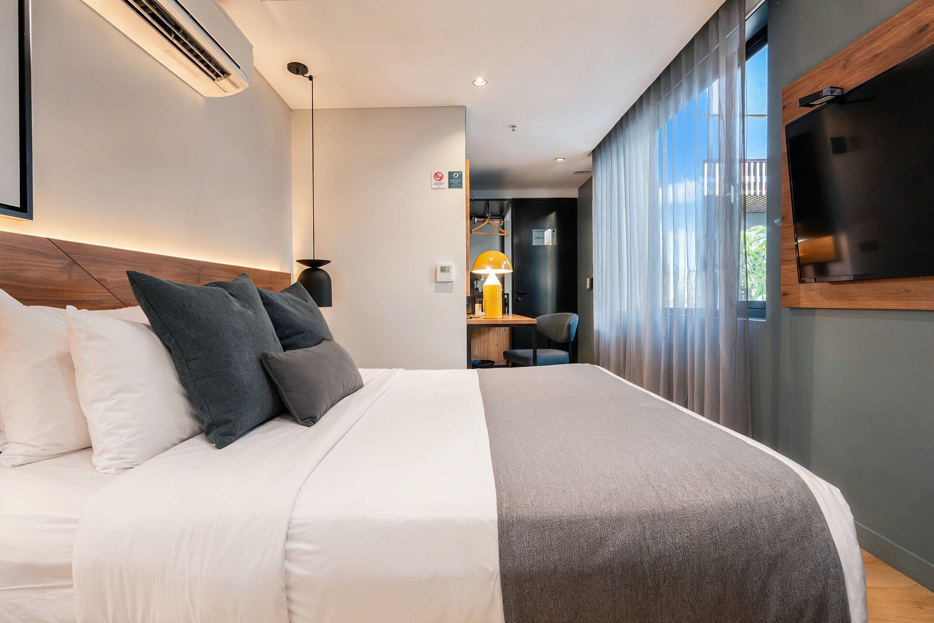 A modern hotel room with a large bed, a desk, and a TV mounted on the wall.