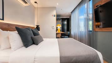 Una habitación de hotel moderna con una cama grande, un escritorio y un televisor montado en la pared.