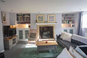 A living room with a fireplace, bookshelves, a sofa, and a television. - Hatfield Cottage, Bath - 3-bed | private garden (Bath)
