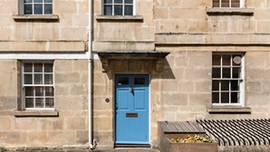 A stone building with a blue door, windows, and a wooden planter with flowers. - Murphy's House Central Townhouse W/courtyard (Bath)