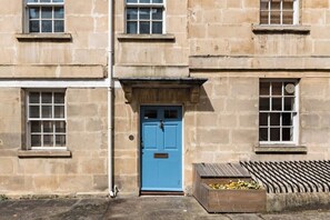 A stone building with a blue door, windows, and a wooden planter with flowers. - Murphy's House Central Townhouse W/courtyard (Bath)