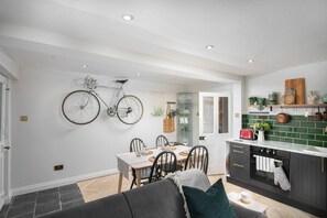 A modern kitchen with a dining area, a bicycle mounted on the wall, and a cozy seating area.