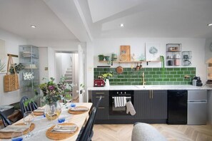 A modern kitchen with dark cabinets, a white countertop, and green backsplash tiles. - The Courtyard - 2 bed Apt in Georgian Townhouse (Bath)