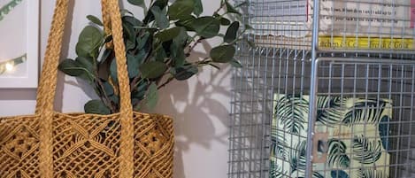 A woven tote bag, a metal birdcage with a patterned cushion, and a framed picture on the wall.