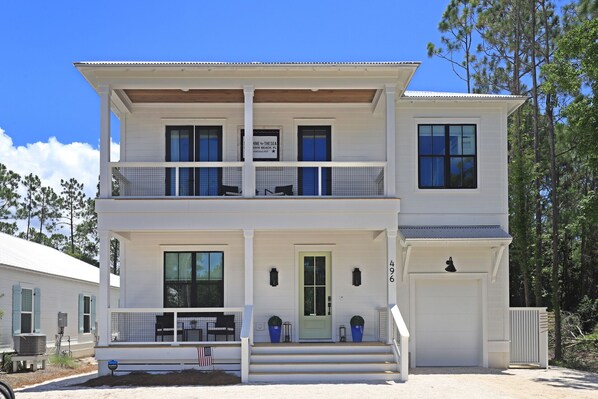 A two-story white house with a balcony, a covered porch, and a garage. - Private Pool | Walk to Seaside, WaterColor | 2 Masters- Sonshine by the Sea (Santa Rosa Beach)