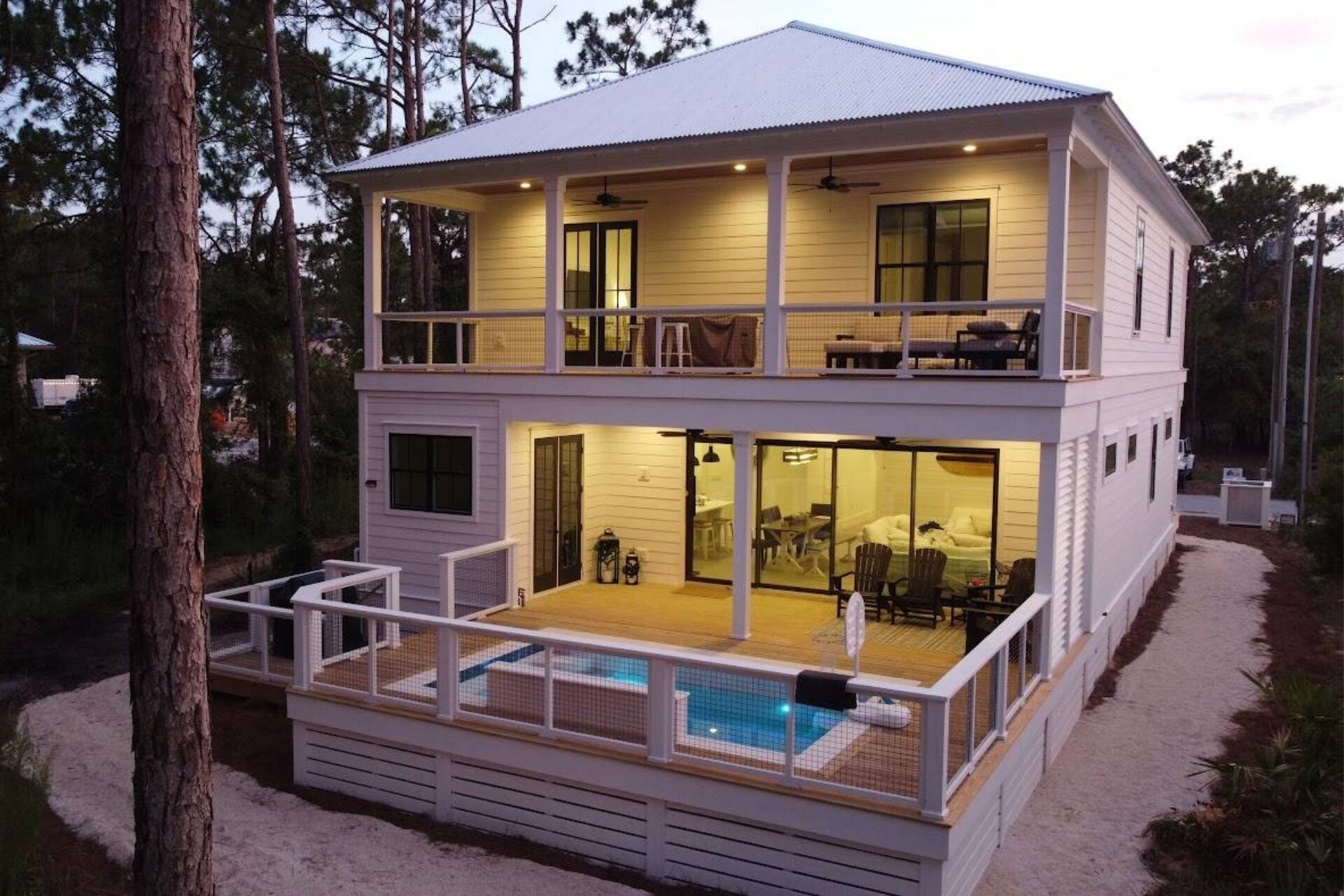 A two-story house with a balcony, a pool, and a covered patio area.