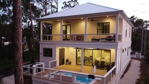 Une maison à deux étages dotée d’un balcon, d’une piscine et d’un patio couvert.