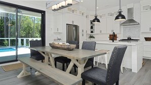 Une cuisine moderne avec des meubles blancs, un îlot central et des luminaires suspendus.