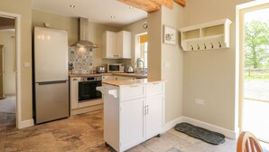 A kitchen with a refrigerator, oven, microwave, and white cabinets. - Acorn Lodge (Stafford)